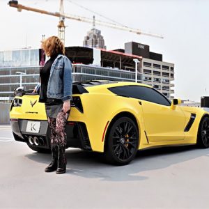 Woman in denim in front of yellow corvette